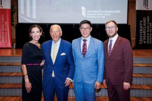 4 Alumni Honors recipients dressed in business attire pose smiling.
