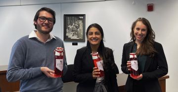 three students holding red objects