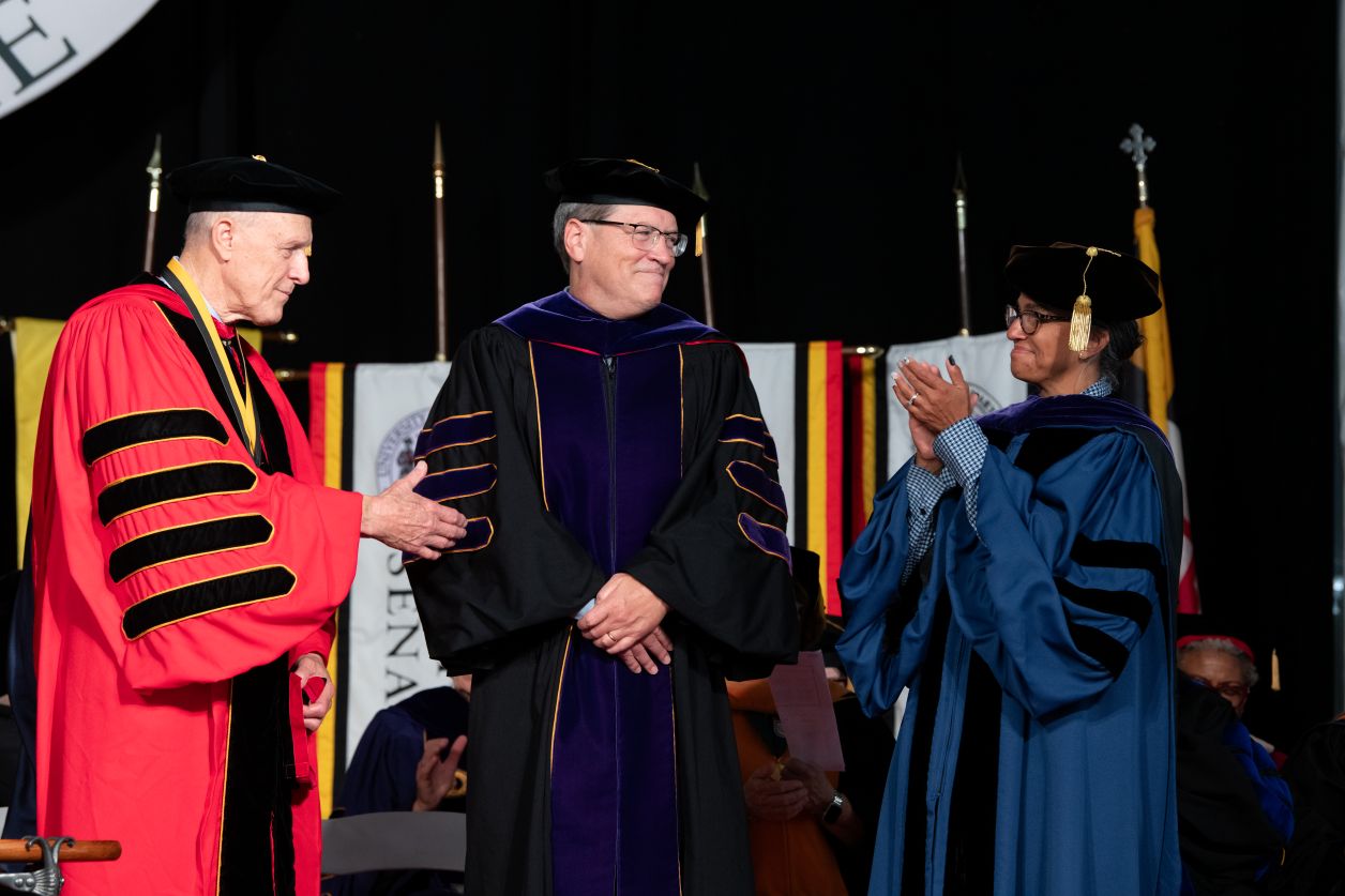 Three academics on stage in regalia.