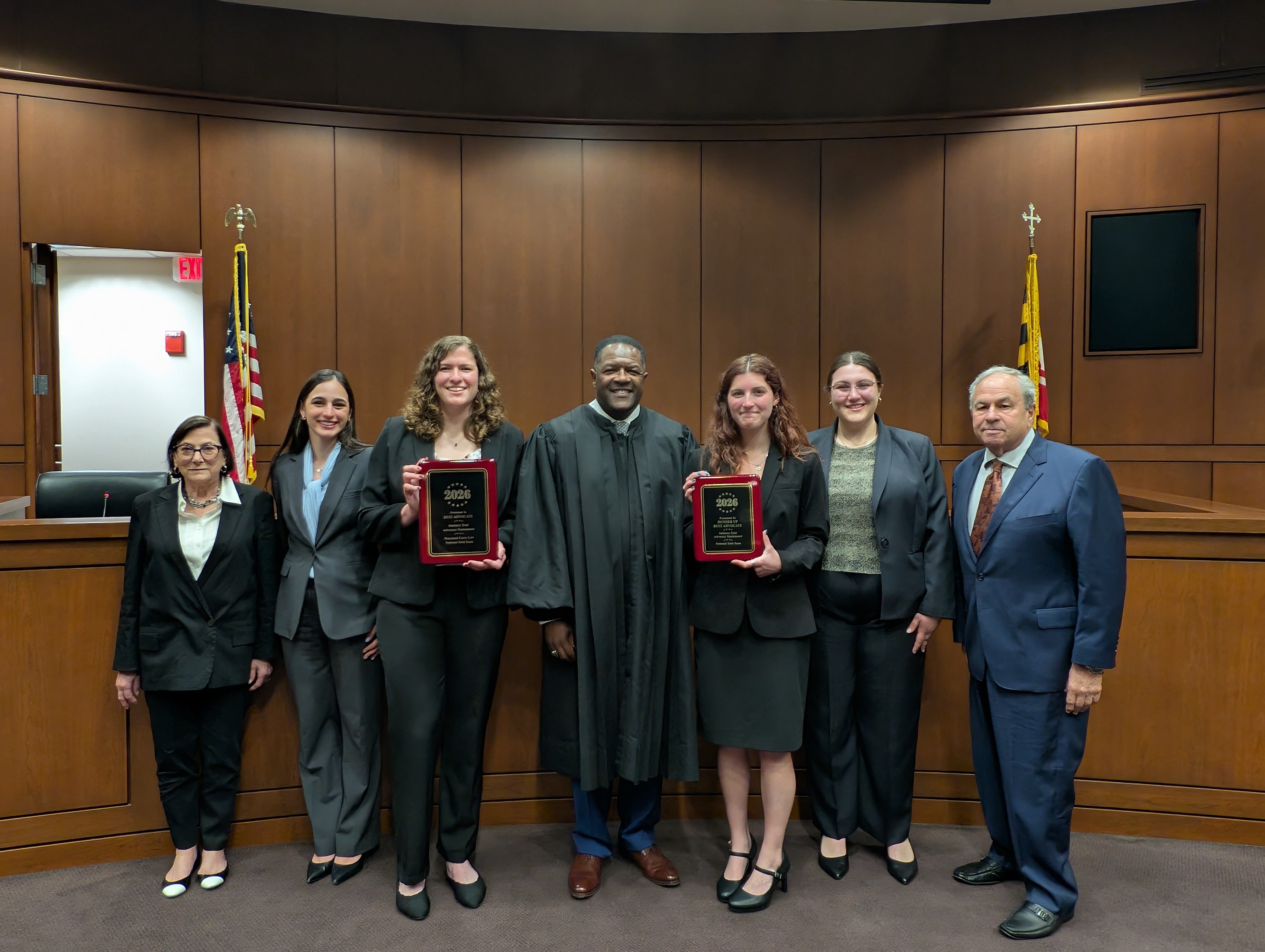 4 finalists pose with 1 judge and 2 supporters in ceremonial courtroom