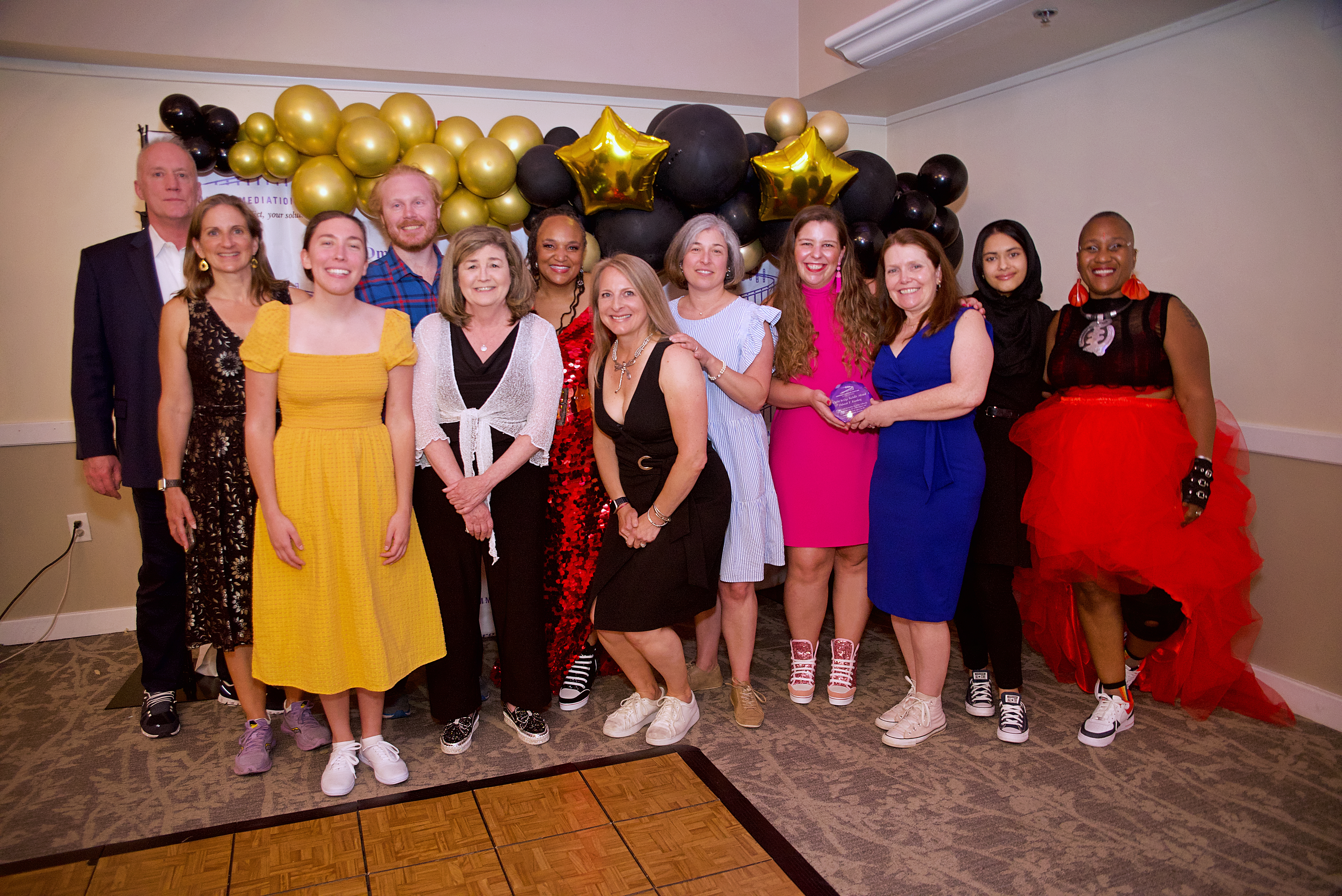 Group posing with an award in front of a balloon arch